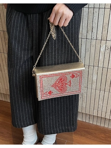 Close-up of gold rhinestone box clutch bag featuring a red Ace of Spades poker pattern