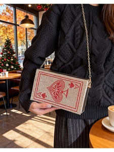 Detail of playing card clutch bag with red rhinestones and gold chain on a model