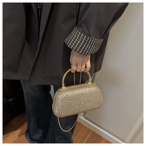 Dettaglio pochette dorata con strass, manico in bambù vintage e tracolla in catena metallica