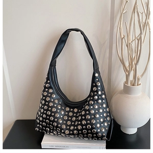 Close-up of black matte PU hobo bag with silver round rivets on a minimalist background