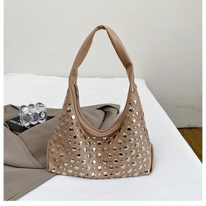 Detail of beige hobo bag with silver rivet studs and soft leather texture on white background