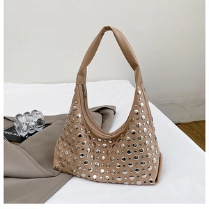Close-up of khaki hobo bucket bag with silver rivets on soft white fabric background