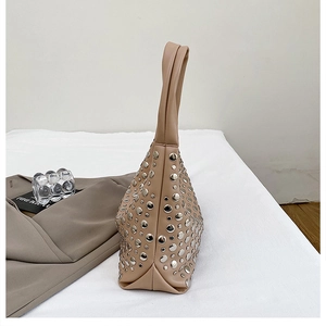 Detail of beige underarm bag showing dense silver metal rivets and synthetic leather texture