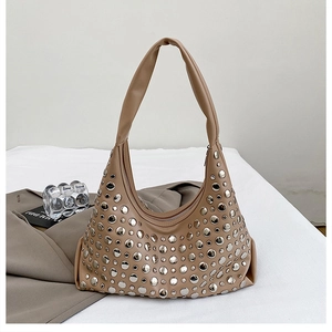 Detailed macro view of silver metallic studs on a khaki leather hobo bucket shoulder bag