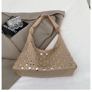 Macro detail of khaki leather shoulder bag with silver rivet studs on suit background