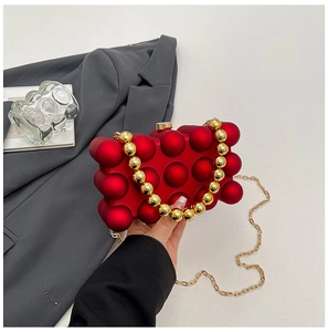 Detail der roten Acryltasche mit Noppenstruktur, goldener Perle und Metallkette