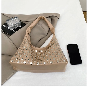Detailed view of khaki hobo bag with silver metallic studs on a white fabric background