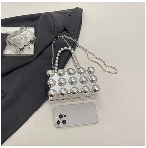 Silberne metallische Eiform-Tasche mit Perlen Griff und Kette neben einem Smartphone