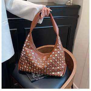 Detail of brown bucket bag featuring silver rivet studs and a knotted handle