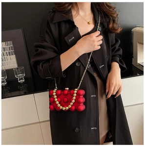 Detail der roten Acryl-Bubble-Clutch mit goldenem Perlengriff und Kettenriemen