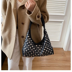 Close-up of black rivet hobo bag with silver studs worn with a tan wool coat