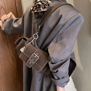 Retro dark brown crossbody bag with silver buckle and chain detail in a stylish pose
