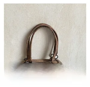 Close-up of reinforced handles on a vintage brown tote bag with metallic stud details