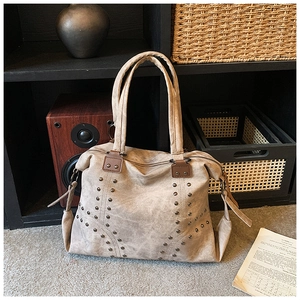 Detailed macro view of khaki canvas tote bag featuring metallic stud accents and long zipper