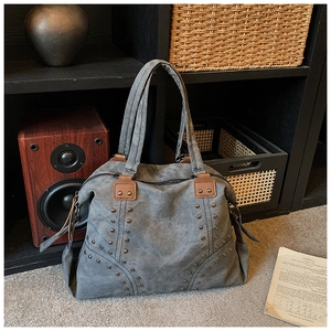 Close-up of vintage canvas tote bag showing bronze rivets and brown leather handles