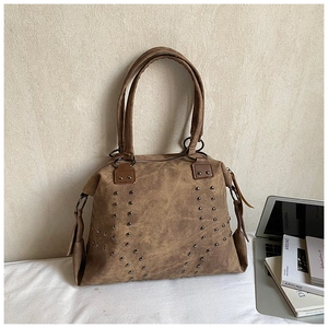 Detail of vintage brown tote bag with metal studs and double handles on a desk