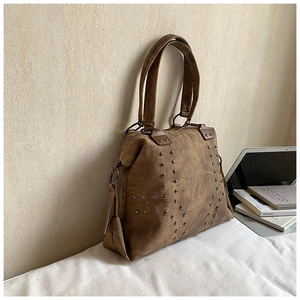 Detail of vintage brown suede tote bag with metallic rivet accents and sturdy handles