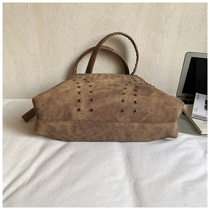 Detail view of large brown faux suede tote bag with metallic stud accents and dual handles