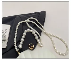 Detail of shell-shaped acrylic evening bag with pearl straps and gold metal hardware