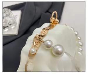 Detail of white shell texture bag with gold hardware and elegant large pearl handle