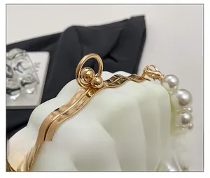 Macro shot of the golden metal clasp and decorative pearls on white shell-shaped bag