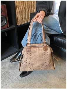 Close-up of vintage brown leather tote featuring stylish metal studs and round ring handles