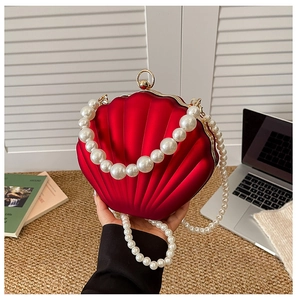 Detail of red shell-shaped evening bag with pleated texture and pearl chain strap