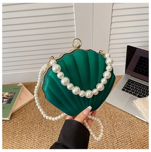 Elegant dark green shell evening bag with white pearl handle and golden metallic clasp