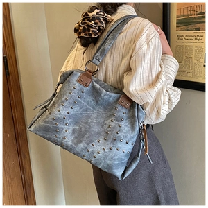 Blue-grey vintage canvas tote bag with metal rivets shown from a side perspective
