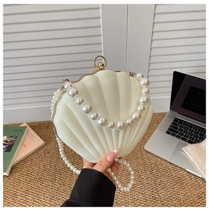 Detail of creative cream seashell clutch bag with pearl handle and metal gold clasp