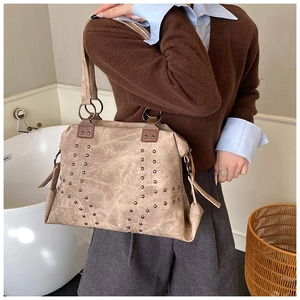 Detail of khaki suede tote bag with metal rivet studs and retro ring hardware