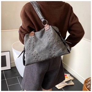 Detail of grey canvas tote bag with silver studs and brown leather handles decoration