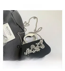 Detail of black evening clutch bag with rhinestone flowers and silver metal handle