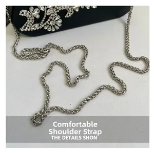 Detailed close-up of crystal floral inlay on a black evening box clutch with silver chain