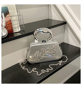 Close-up of silver rhinestone floral pattern and metal U-handle on hard shell evening bag