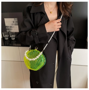 Detail of neon green shell crossbody bag with acrylic texture and large pearl strap