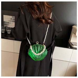 Detail of green acrylic shell bag featuring pearl chains and golden metal clasp