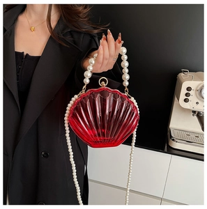 Detail of red acrylic shell bag with large pearl handle and long crossbody pearl strap