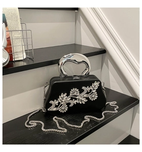 Detail of black box clutch with crystal floral embroidery and silver metal handle