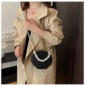 Detail of shell-shaped black acrylic evening bag with faux pearl handles and chain