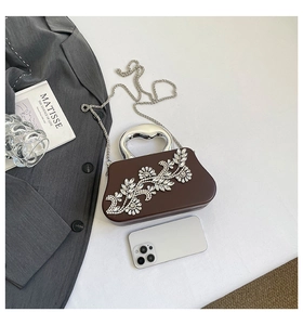 Detail of brown leather box clutch with crystal floral pattern and silver top handle