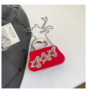 Detail of red satin evening bag featuring rhinestone floral pattern and metal handle