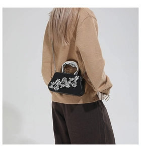 Detail of rhinestone floral clutch with silver metallic handle and chain on model