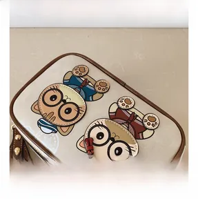 Detail of beige camera bag featuring cartoon cats and premium brown leather piping