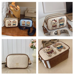 Detail view of cartoon cat camera bags with wide adjustable straps in cream and blue
