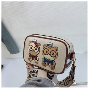 Detail of cute cat illustration and wide jacquard strap on beige camera crossbody bag