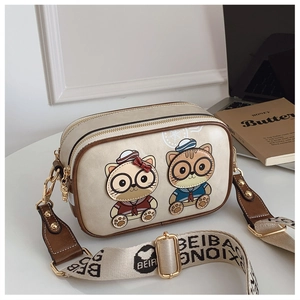 Detail of cute cartoon cat patches on a cream crossbody bag with wide jacquard strap