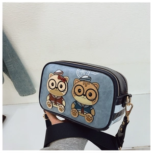 Detail of cute cartoon cat printing and gold zipper on a blue crossbody camera bag