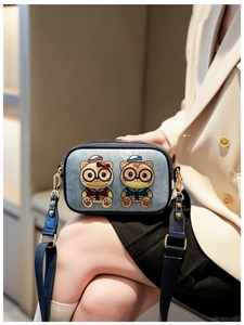 Detail of blue camera bag featuring 3D cartoon cats with intricate embroidery texture