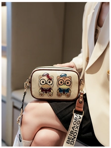 Detail of cute cartoon cat embroidery on beige square bag with wide branded shoulder strap